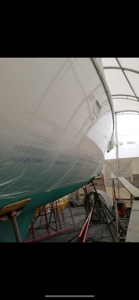 Professional paint booth setup with covered boat